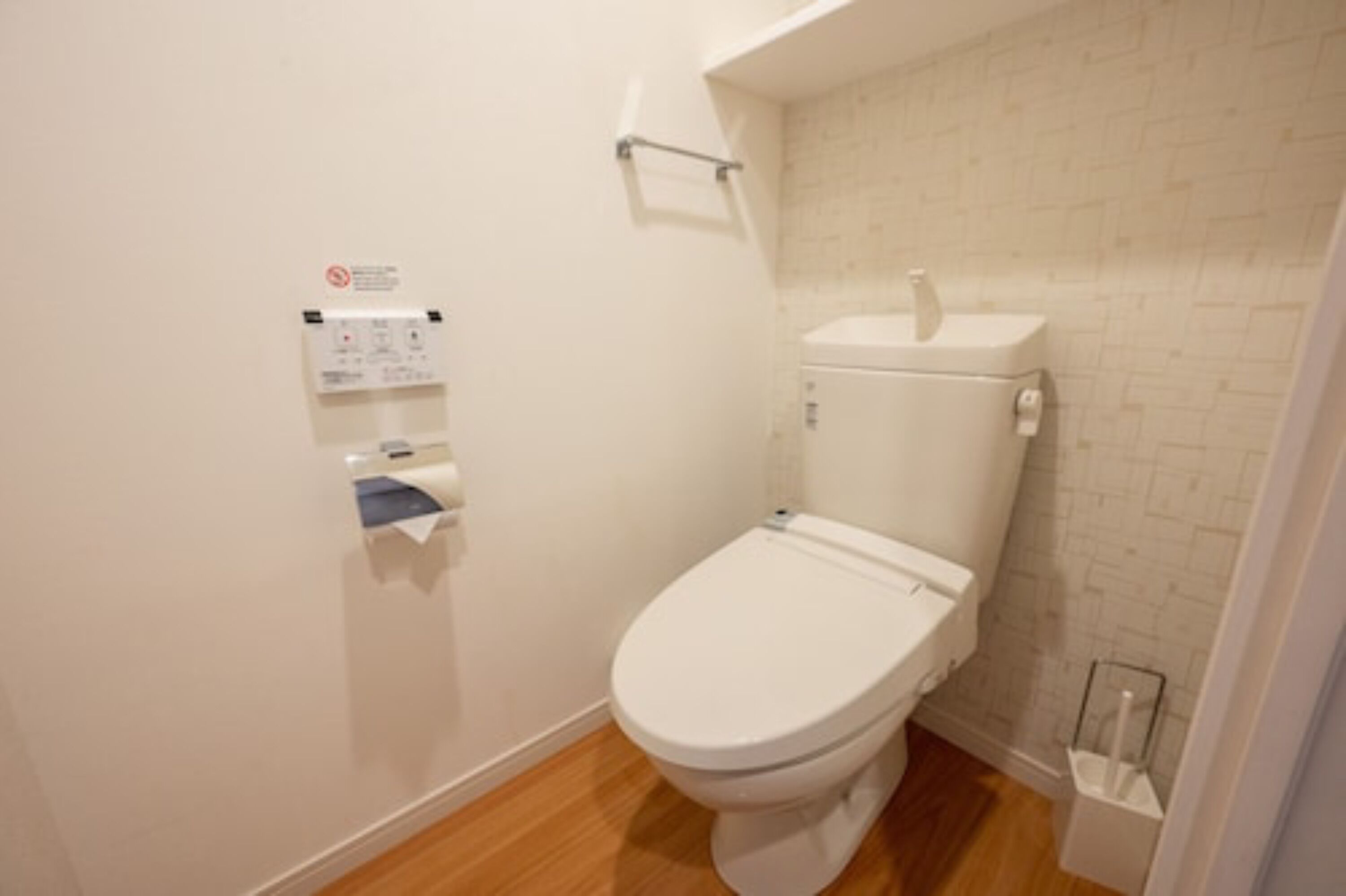 A small, clean bathroom with a white toilet, a white sink, and a white trash bin.