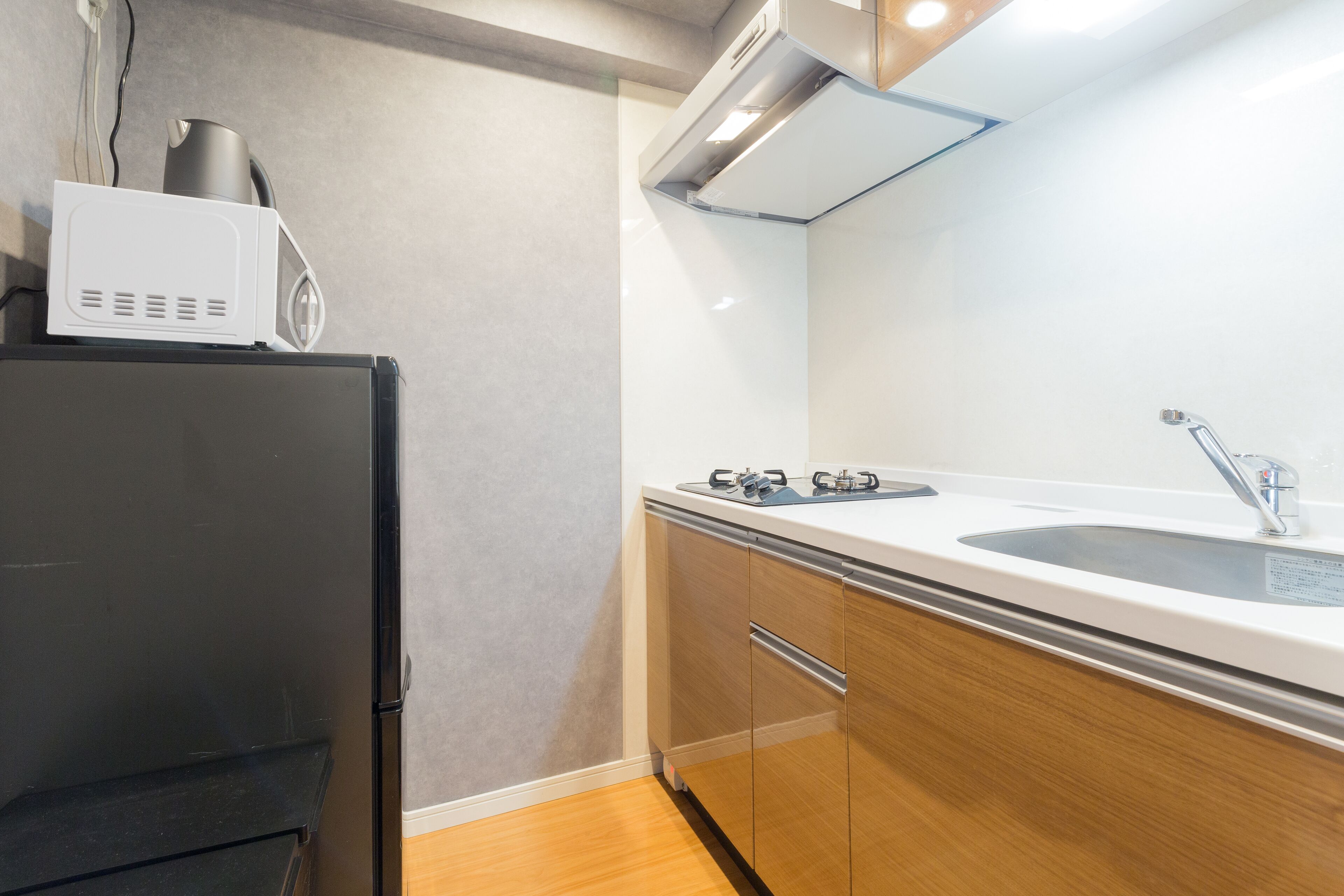 Une cuisine compacte équipée d’un four à micro-ondes, d’une cuisinière, d’un évier et d’armoires en bois.