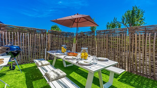 Eine Terrasse mit Esstisch, Grill und einer Sitzgelegenheit mit Pergola.