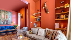Ein gemütliches Wohnzimmer mit einer Eckcouch, einem Couchtisch mit Kerze und einem Bücherregal mit Dekoration.