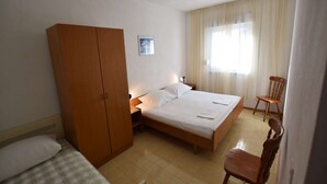 Une chambre d’hôtel avec un lit simple, une armoire en bois, une chaise et une petite table.