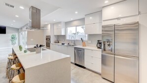 Uma cozinha moderna com uma ilha central, eletrodomésticos de aço inoxidável e uma janela ampla.