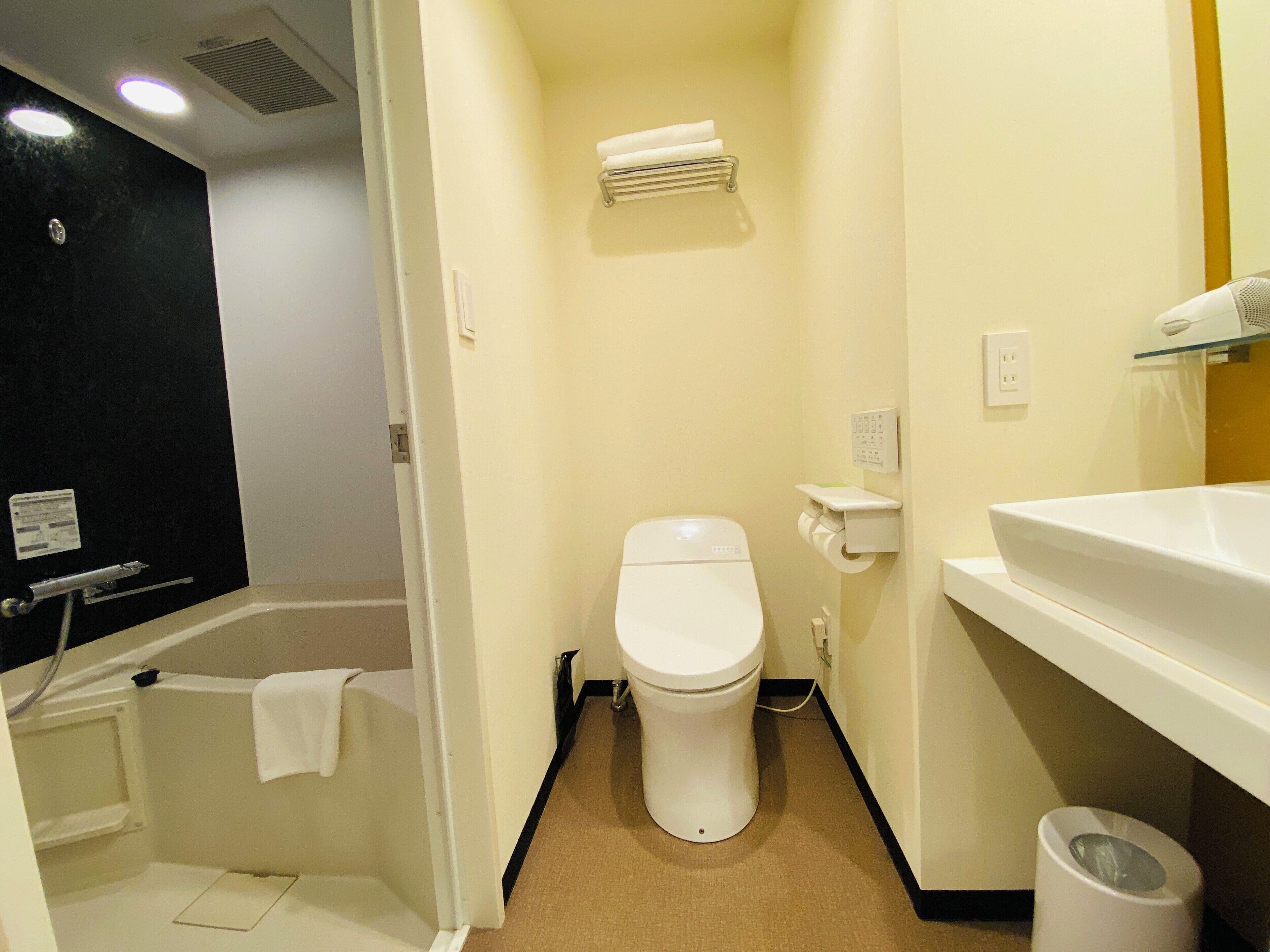 A small, modern bathroom with a toilet, a sink, and a shower area.