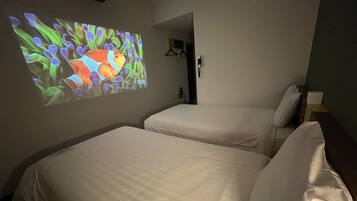 A hotel room with two beds, a wall-mounted projector displaying a colorful image, and a door leading to another room.