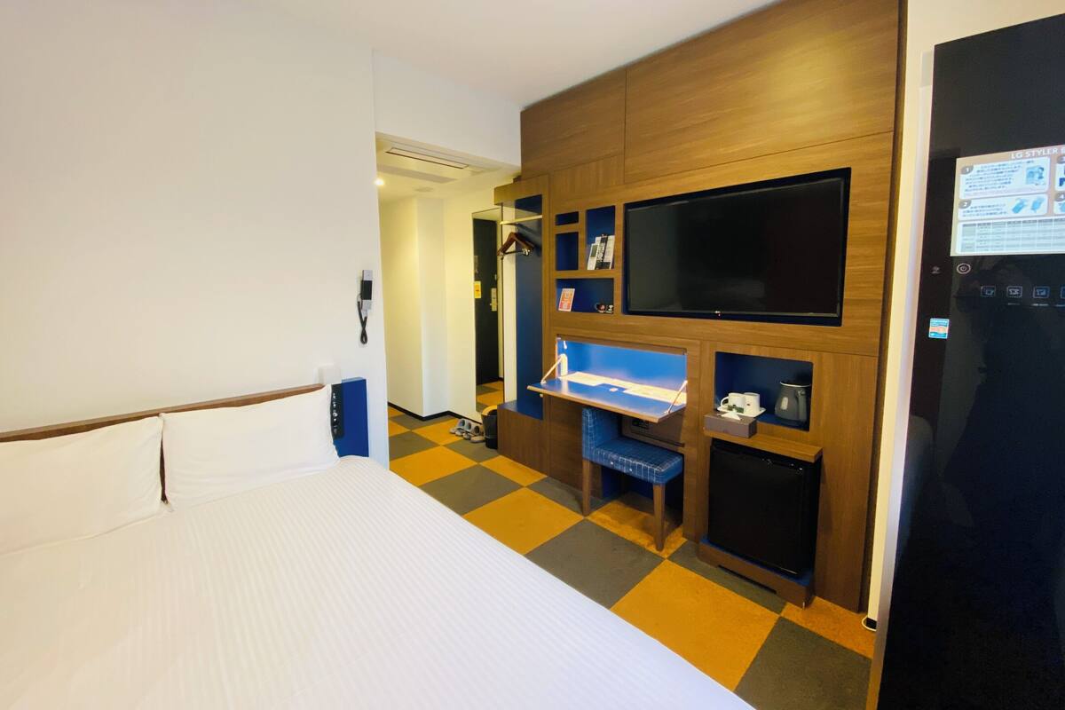 Ein Hotelzimmer mit Bett, Fernseher, Schreibtisch und Kleiderschrank.