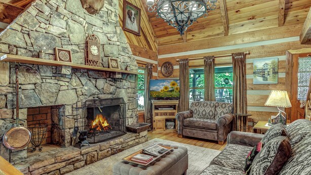 Un salón acogedor con chimenea de piedra, asientos cómodos y un gran ventanal con cortinas.