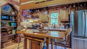 Una cocina rústica con armarios de madera, un refrigerador de acero inoxidable y una mesa de comedor de madera.