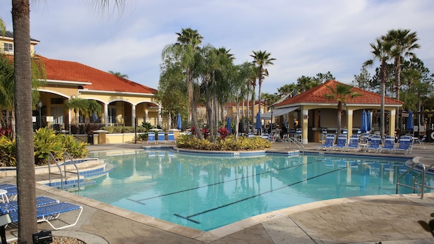 A swimming pool with lounge chairs and palm trees. - Family friendly villa, gated community, spa, heated pool, close to theme parks. (Kissimmee)