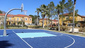 A basketball court with a blue surface, a hoop, and surrounding trees. - Family friendly villa, gated community, spa, heated pool, close to theme parks. (Kissimmee)