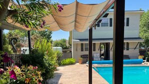 A covered patio area with a pool, lounge chairs, and potted plants. - Luxury Living in a Country Setting and Minutes to Lubbock! (Wolfforth)