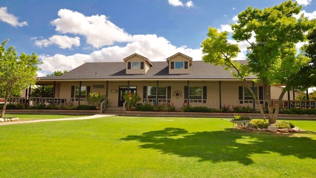 A two-story building with a flat roof, a front porch, and a well-maintained lawn. - Luxury Living in a Country Setting and Minutes to Lubbock! (Wolfforth)