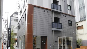 Un hôtel moderne à la façade grise, doté de grandes fenêtres et d’une entrée bien visible.