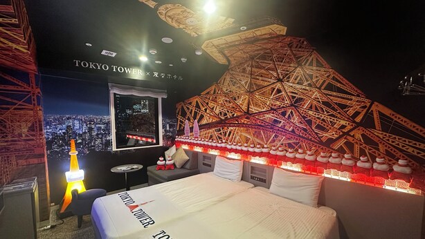 Une chambre d’hôtel avec un lit, une petite table et une chaise. Il y a une grande fenêtre qui offre une vue sur la ville.