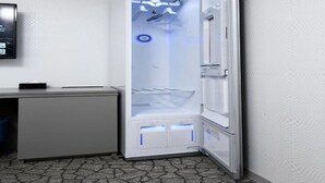 Une chambre compacte et moderne, dotée d’un réfrigérateur intégré, d’un petit bureau avec un ordinateur et d’un tapis à motifs.