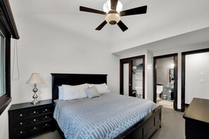 A bedroom with a bed, a nightstand, a lamp, and a ceiling fan.