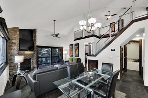 Un salon moderne avec une table à manger en verre, un canapé en cuir et une cheminée en pierre.