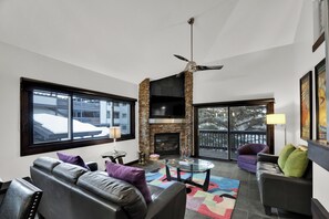 Un salon moderne avec une cheminée, des canapés en cuir, une table basse en verre et un balcon avec vue.