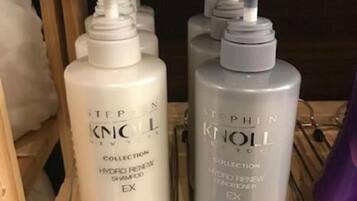 Two bottles of Stephen Knox hydro renew shampoo on a wooden shelf.