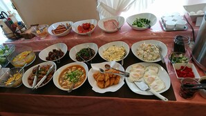 Een buffettafel met diverse gerechten, zoals eieren, worstjes en salades.