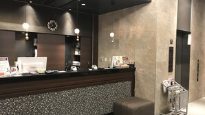 Een hotel receptie met een donker aanrecht, een digitale klok en een receptiebalie.