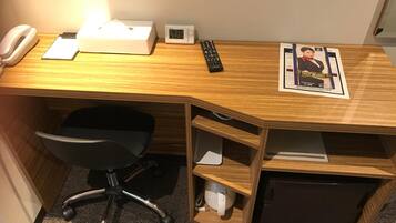 A wooden desk with a tissue box, a clock, a remote control, and a poster.