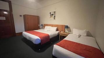 Habitación de hotel con dos camas, un armario, un cuadro en la pared y una lámpara en el techo.