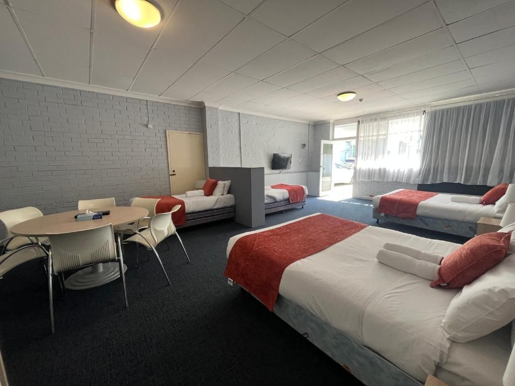 A hotel room with a bed, a desk, a chair, and a television.