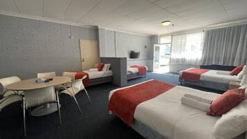 A hotel room with a bed, a desk, a chair, and a television.