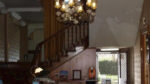 Una majestuosa escalera con candelabro, un mostrador de recepción y vistas a través de un ventanal.
