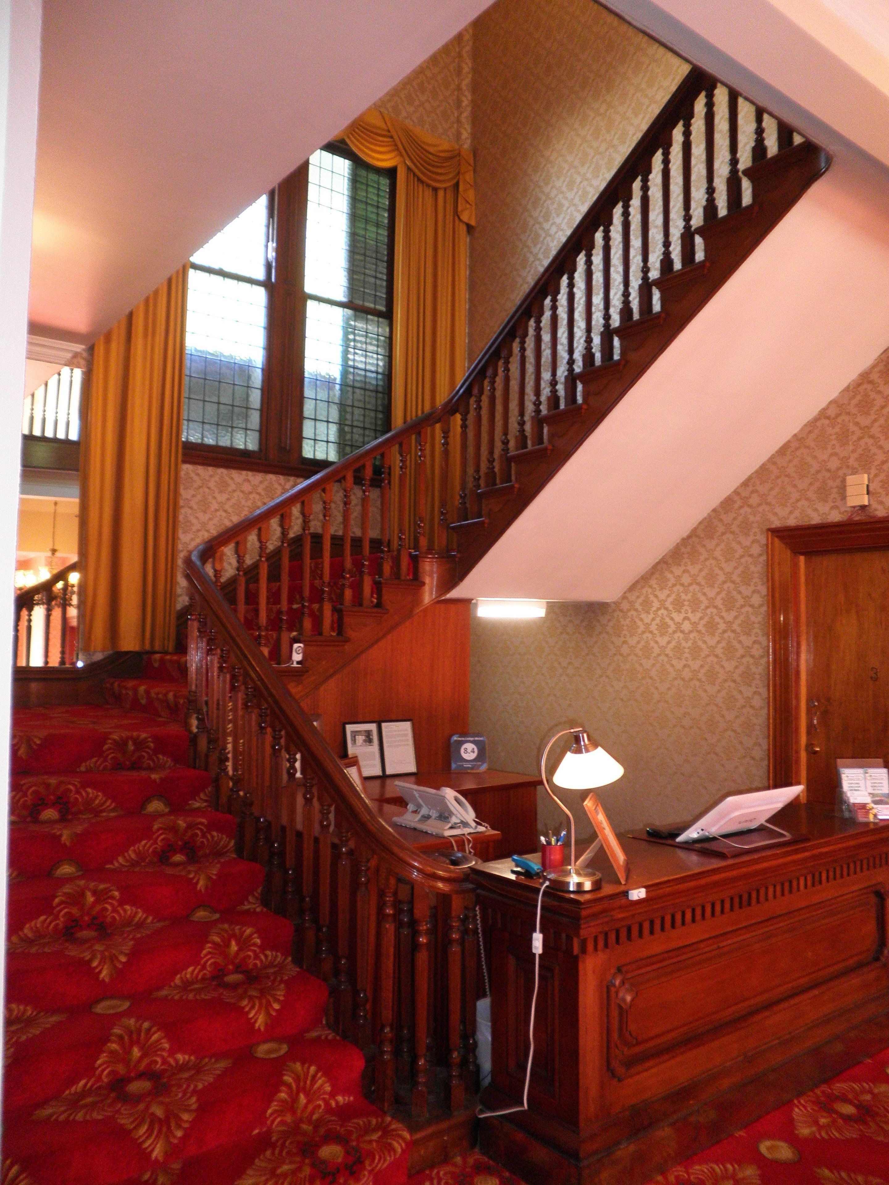 A staircase with wooden balusters and a red carpeted landing area.
