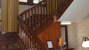 Una amplia escalera con detalles de madera ornamentados y un elegante suelo estampado.