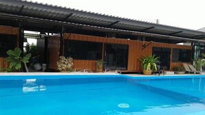 A modern poolside area with a clear blue pool, wooden deck, and potted plants. - Rintara Riverside Resort (Klaeng)