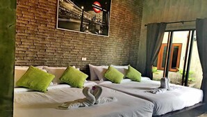 A hotel room with two beds, green pillows, a swan towel, and a London Underground sign on the wall. - Rintara Riverside Resort (Klaeng)