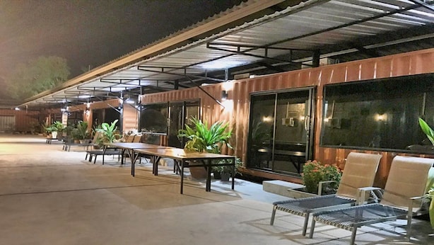 An outdoor patio area with tables and chairs, potted plants, and a covered seating area. - Rintara Riverside Resort (Klaeng)