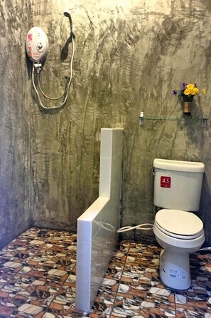 A bathroom with a toilet, a shower, and a marble-tiled floor.