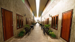 A hotel corridor with wooden doors, potted plants, and a central walkway. - Rintara Riverside Resort (Klaeng)