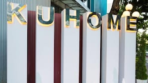 A hotel entrance with illuminated letters spelling "KUHOME" and two fountains in front. - KU Home Hotel (Bangkok)