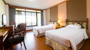 A hotel room with two single beds, a desk with a computer, a chair, and a large window with blinds. - KU Home Hotel (Bangkok)