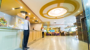 A hotel reception area with a counter, seating area, and a modern ceiling design. - KU Home Hotel (Bangkok)