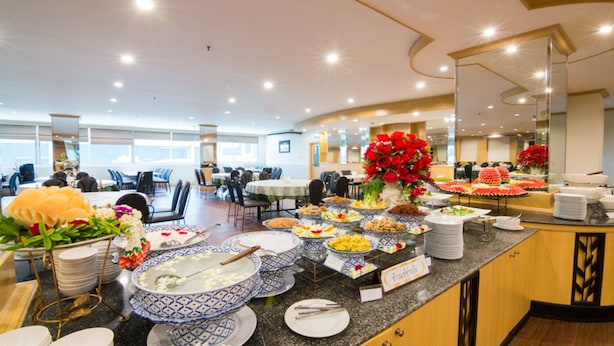 A buffet setup with various food items and a large floral centerpiece. - KU Home Hotel (Bangkok)