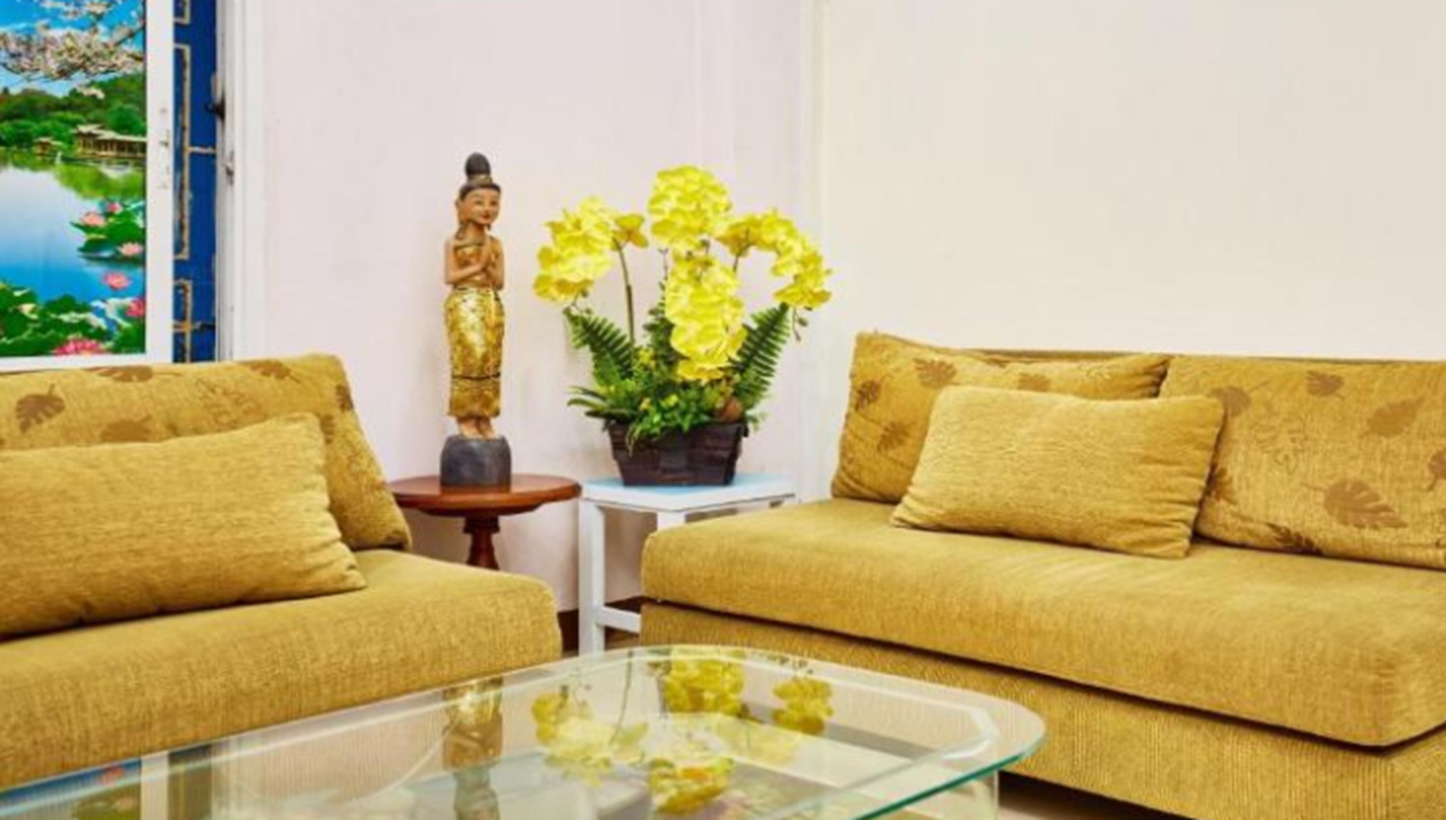 A living room with two sofas, a small table, a statue, and a potted plant.