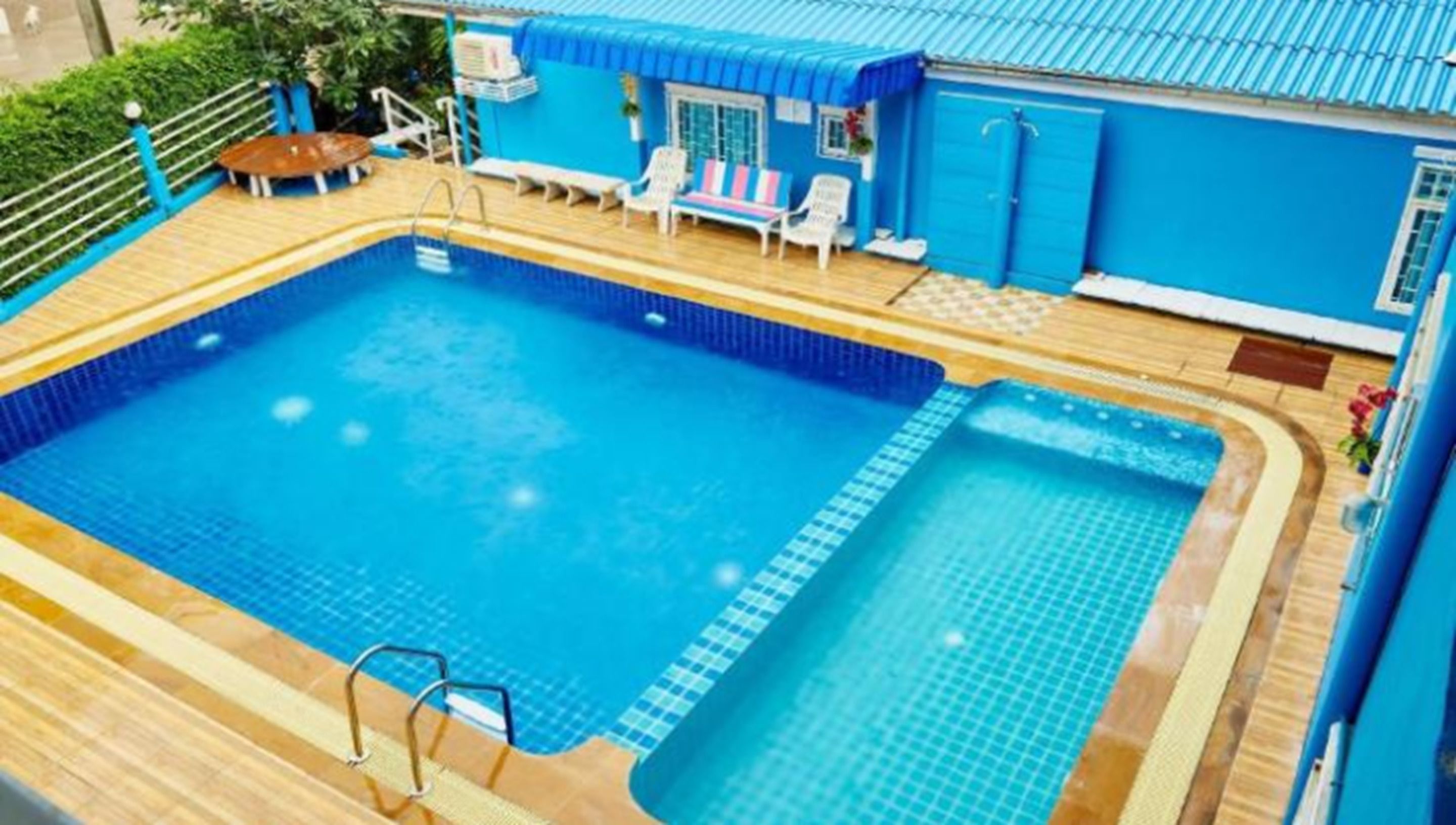 Una piscina con cubierta de madera, un jacuzzi pequeño y un área de descanso con sillas y una mesa.