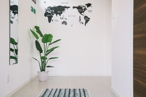 A hallway with a world map mural, a potted plant, and a striped rug. - United Resort Sarabeth (Onna)
