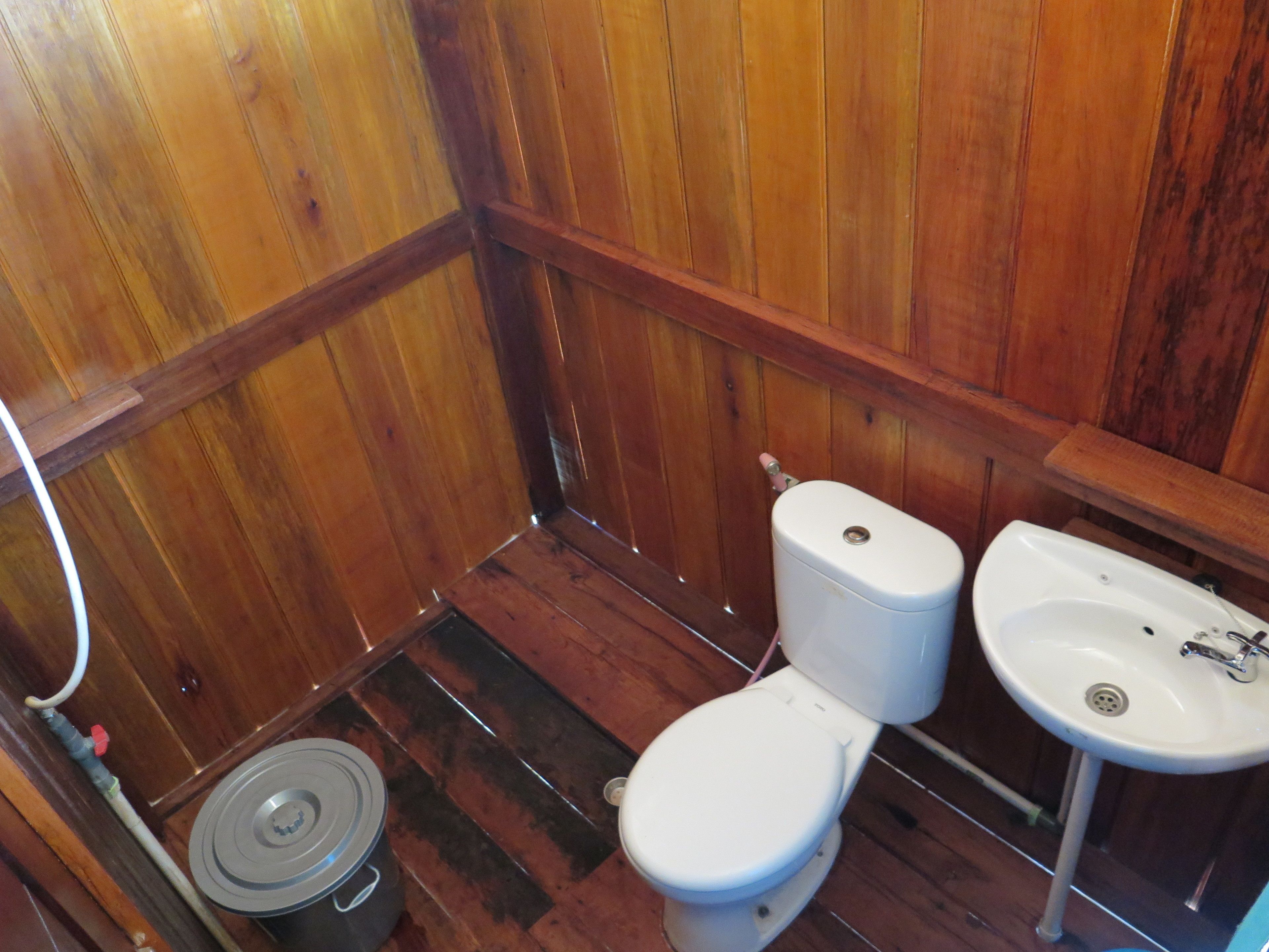 Un baño pequeño con piso de madera, un inodoro y un lavamanos.