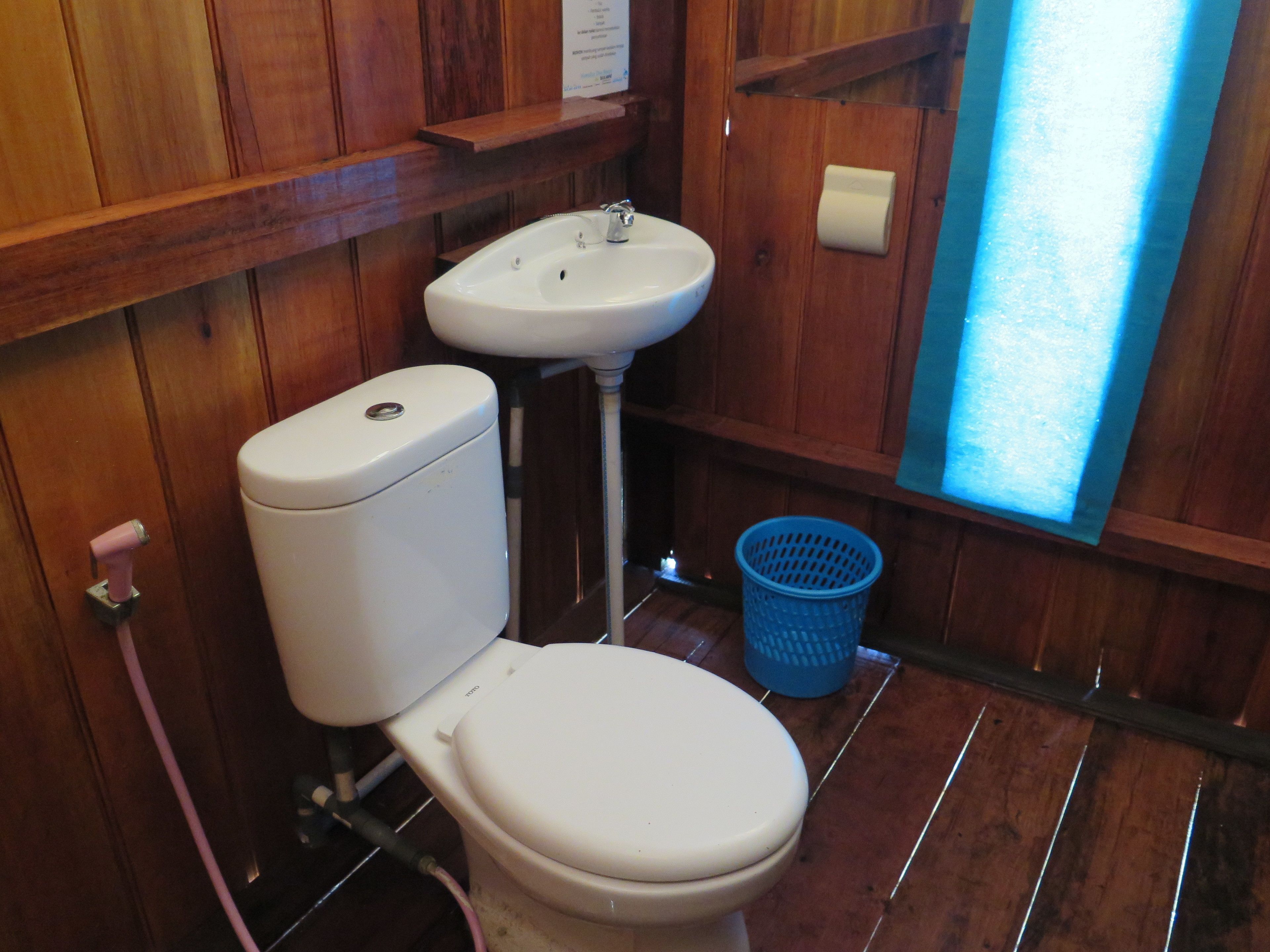 A small bathroom with a toilet, sink, and a blue laundry basket.