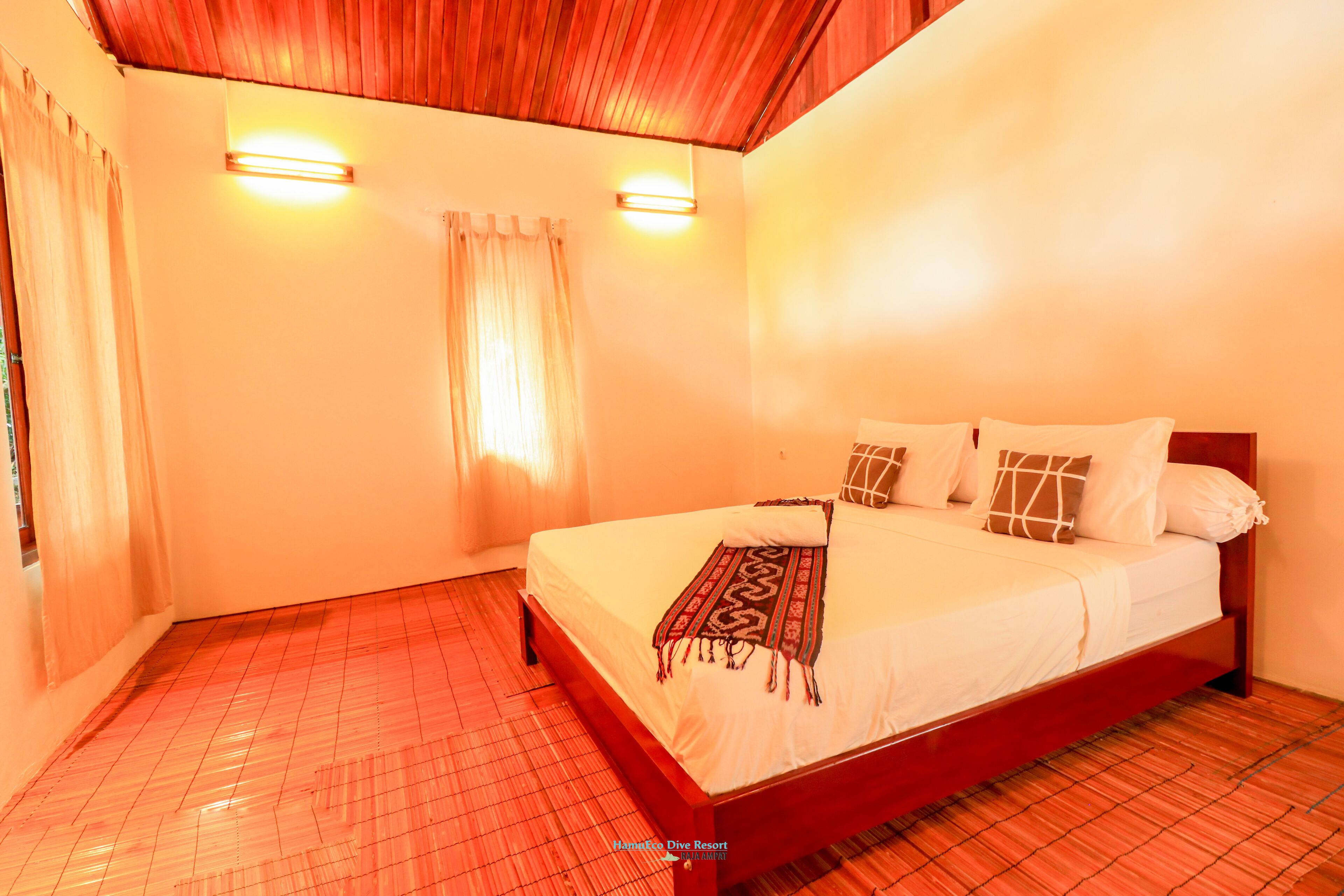 A bedroom with a wooden bed frame, a white bedspread, and two wall-mounted lights.