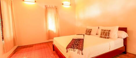 A bedroom with a wooden bed frame, a white bedspread, and two wall-mounted lights.