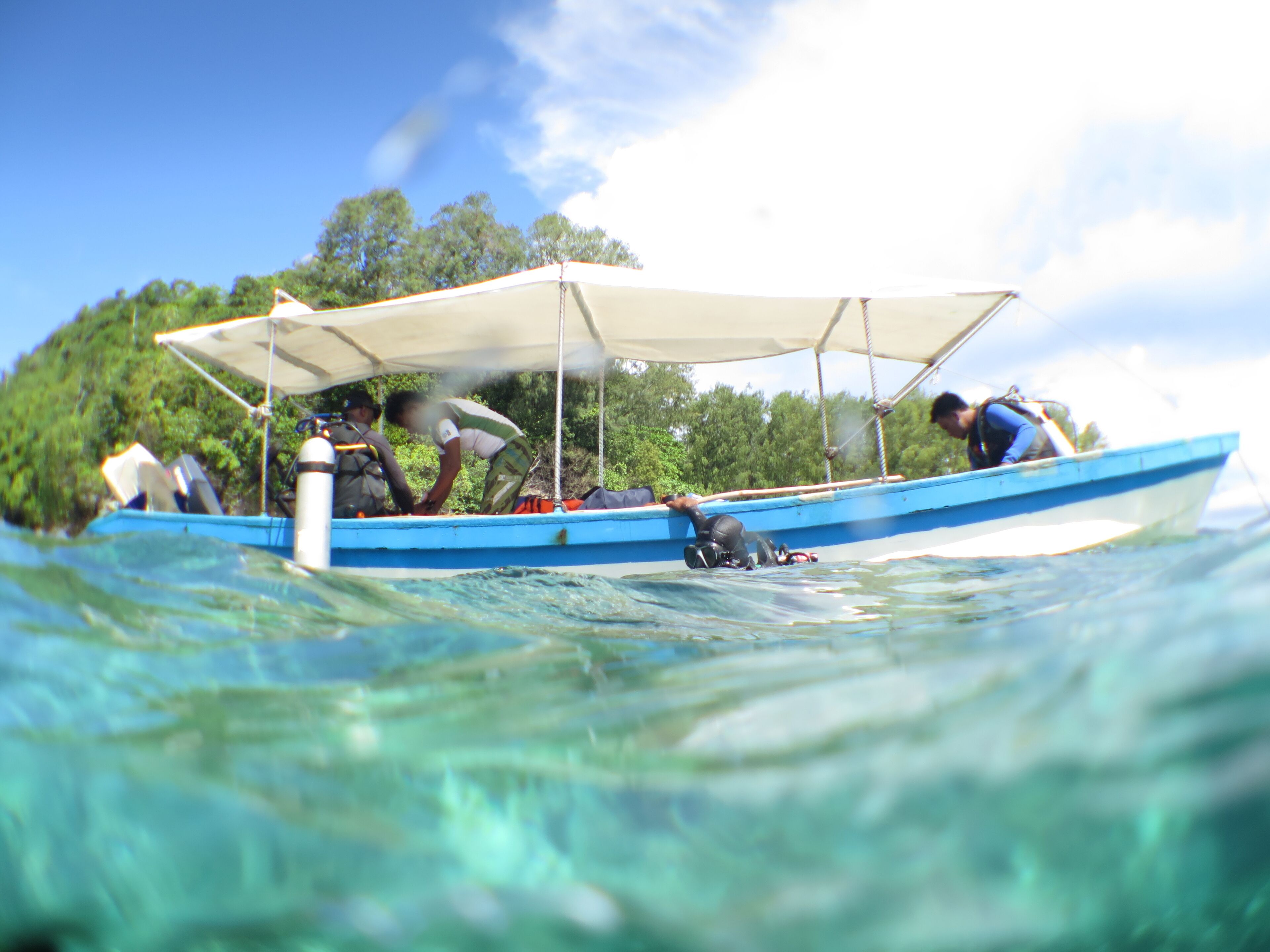 A boat with a canopy, people on board, and water.