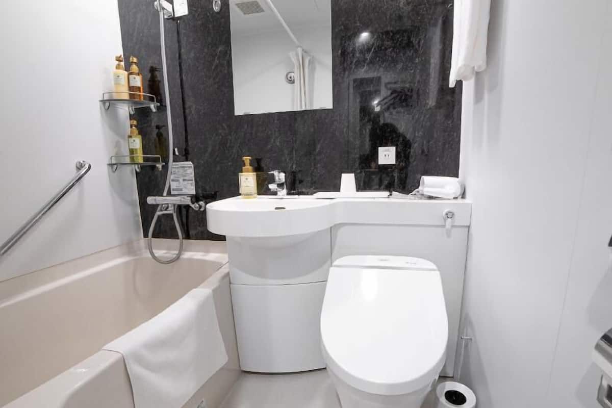 A modern bathroom with a bathtub, toilet, and a shower area.