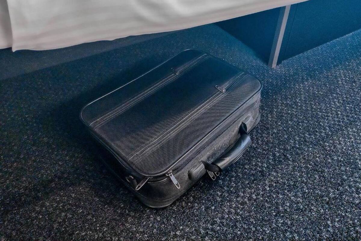 A black suitcase on a textured carpet.